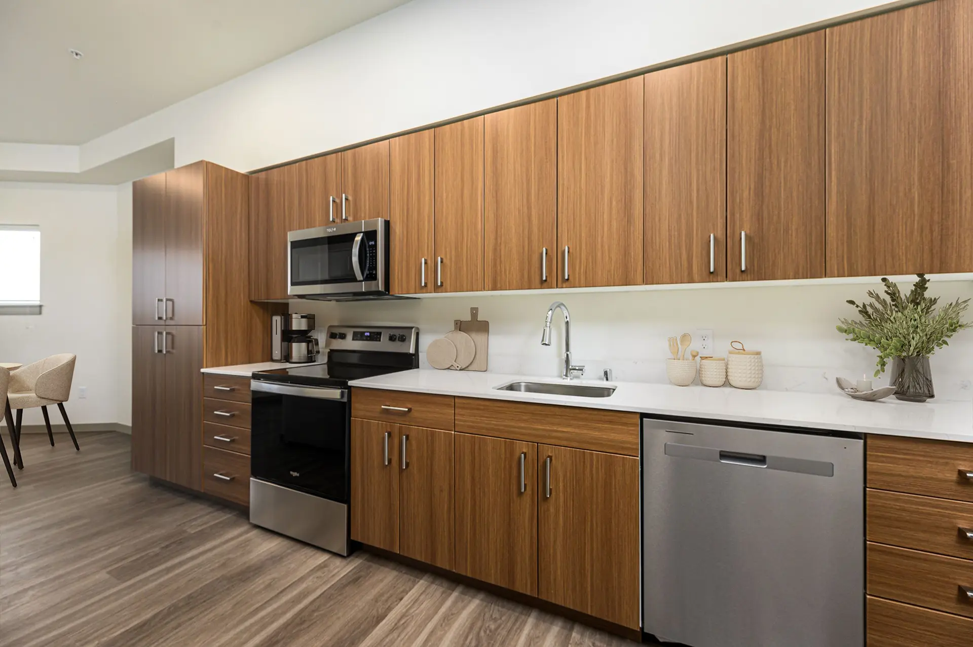 galley kitchen with brown custom cabinets, stainless appliances, and sink between a glass top stove and dishwasher.