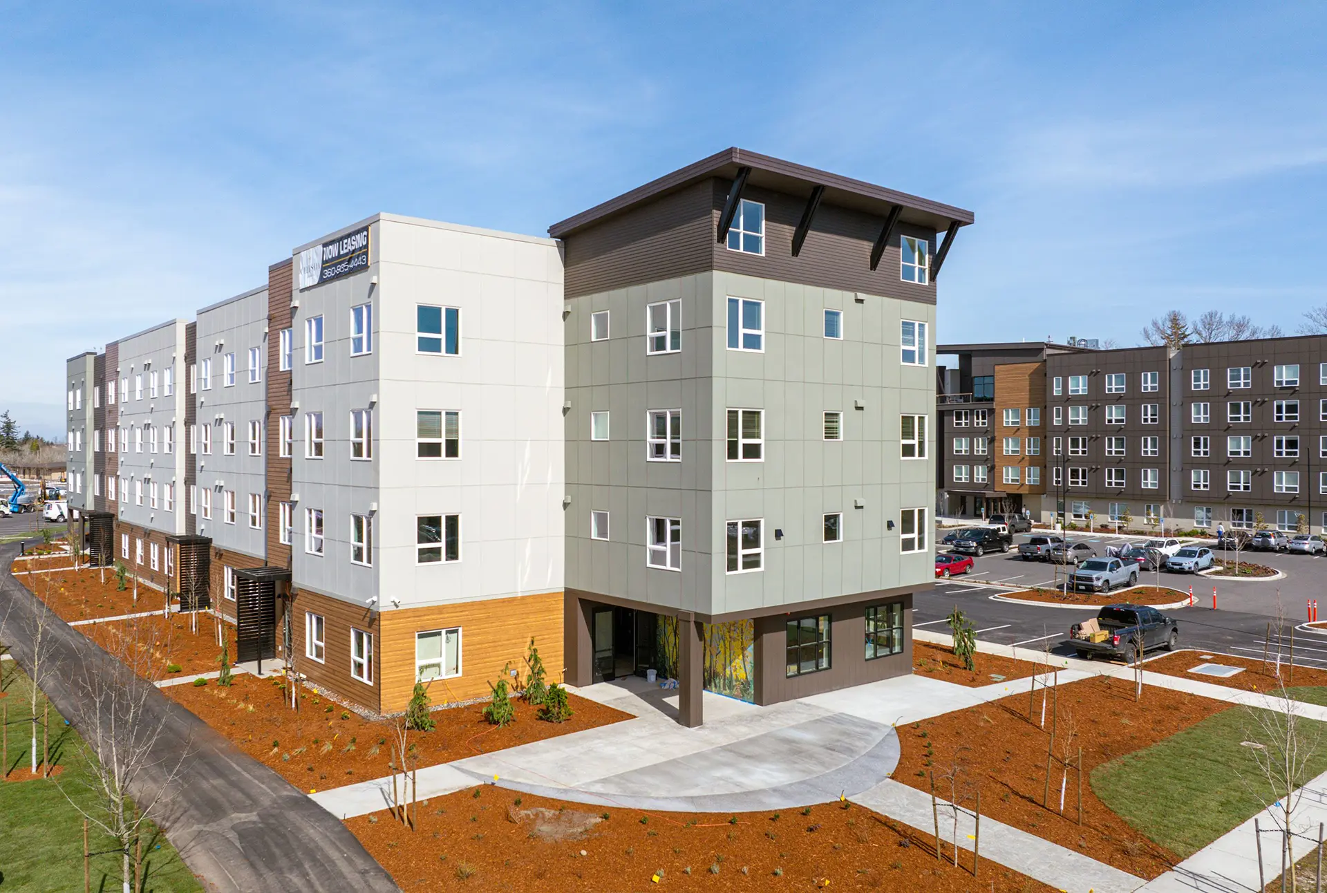 ground level view of the end of Celestia at Cordata building with cream and green siding on top and light brown siding on the bottom. The building has a boxy modern architecture style.