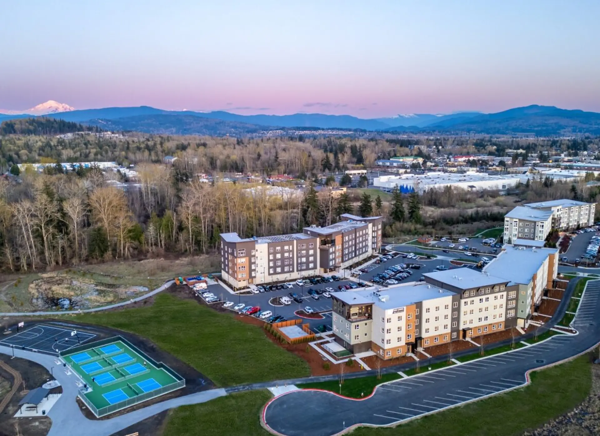 birds eye view of apartment community with two long buildings and mountains in the background at sunset