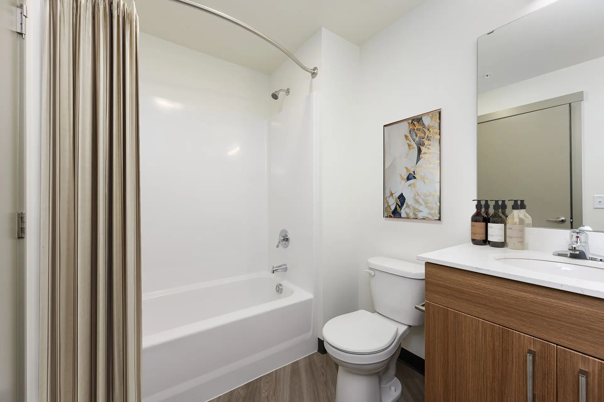 bathroom with single vanity next the toilet and a shower/tub combo with curved curtain rod.