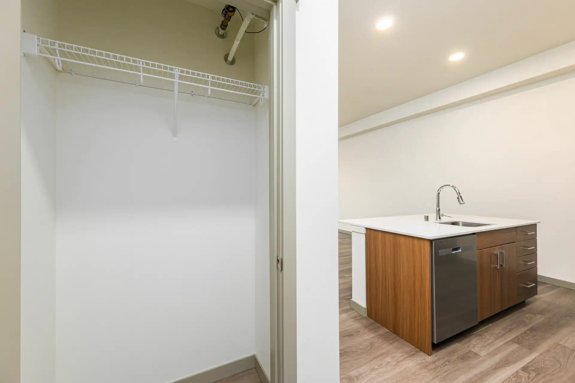 open hallway coat closet with wire shelf, and open kitchen with large island on the right