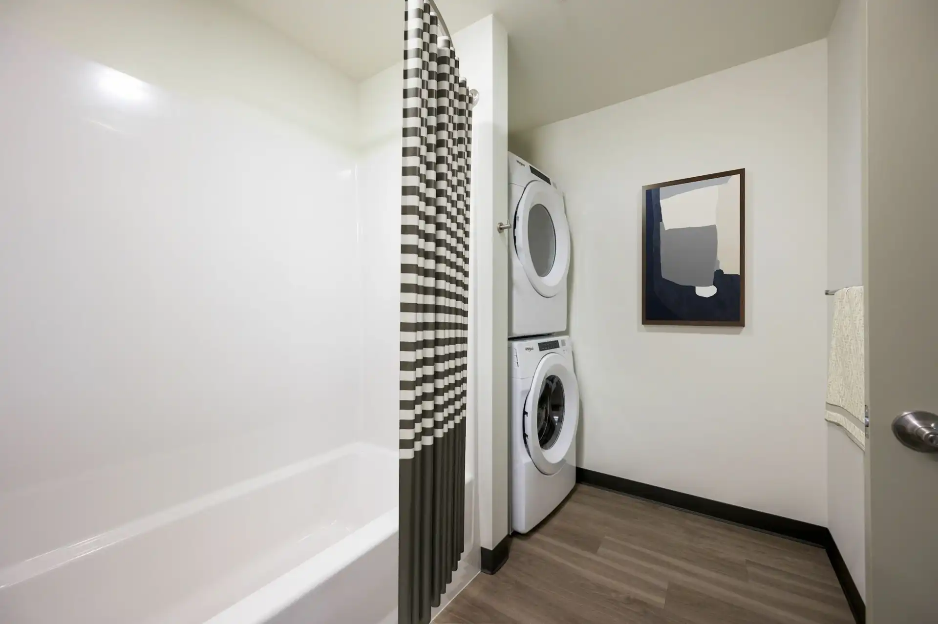 bathroom with stacked front loading washer and dryer next to the bathtub.