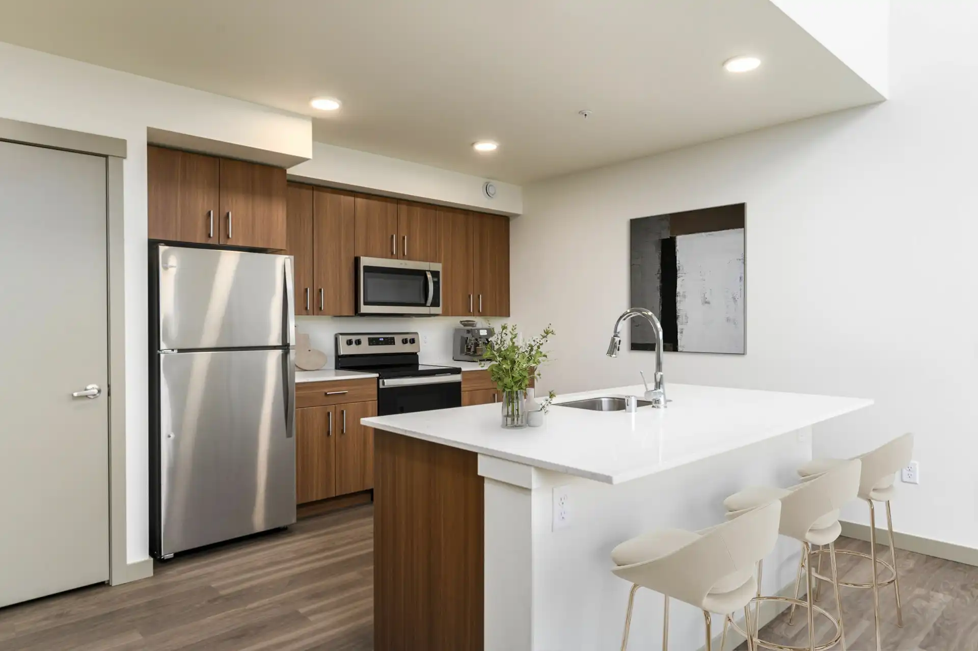 Open kitchen. A large island with a sink has bar seating with three stools separating it from the living room.