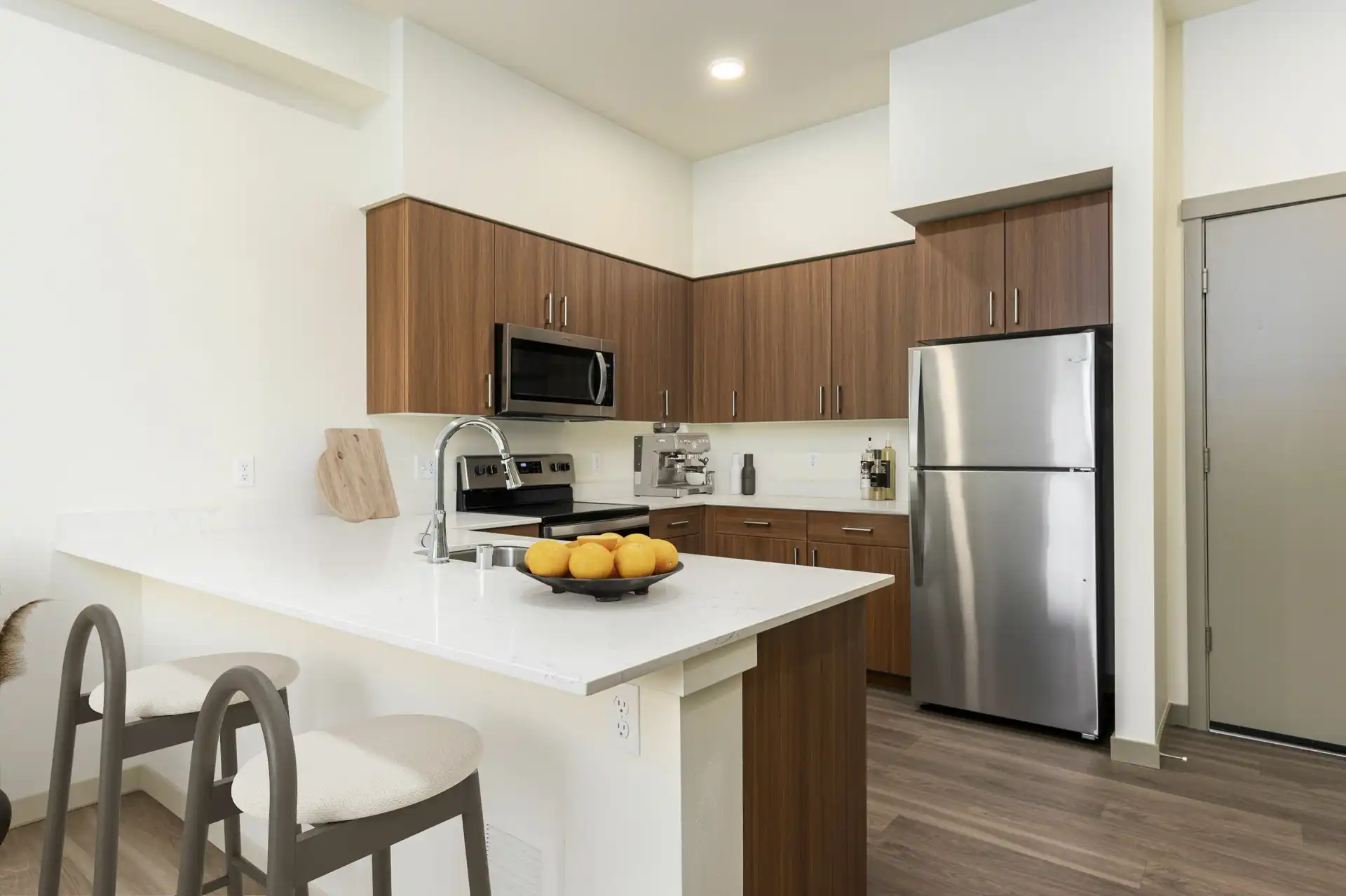 open kitchen with white countertops and bar seating with two stools.